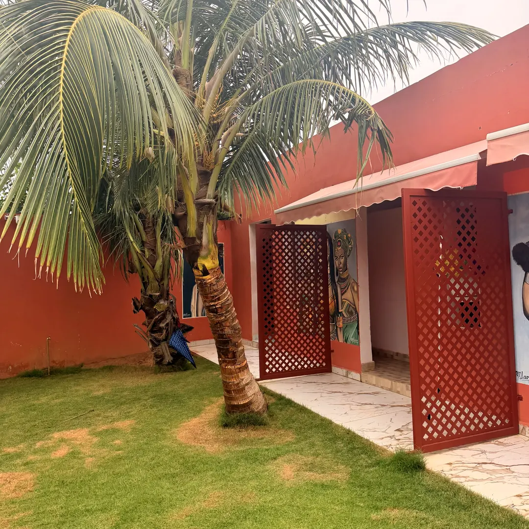 Cocotier devant les claustras rouges et les fresques d'artistes de la cour