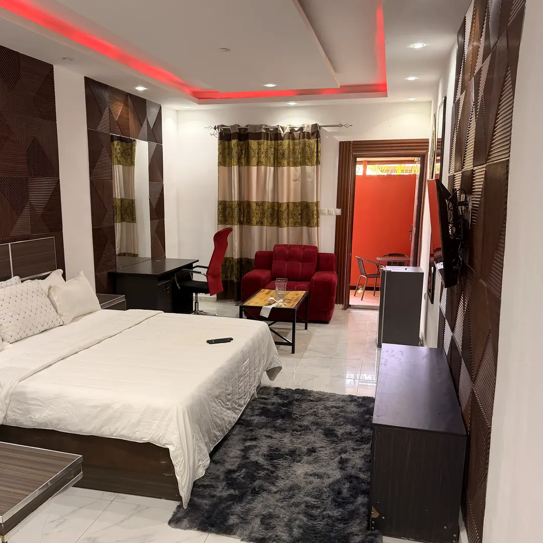 Coin salon de la suite avec fauteuil rouge et accès à la terrasse